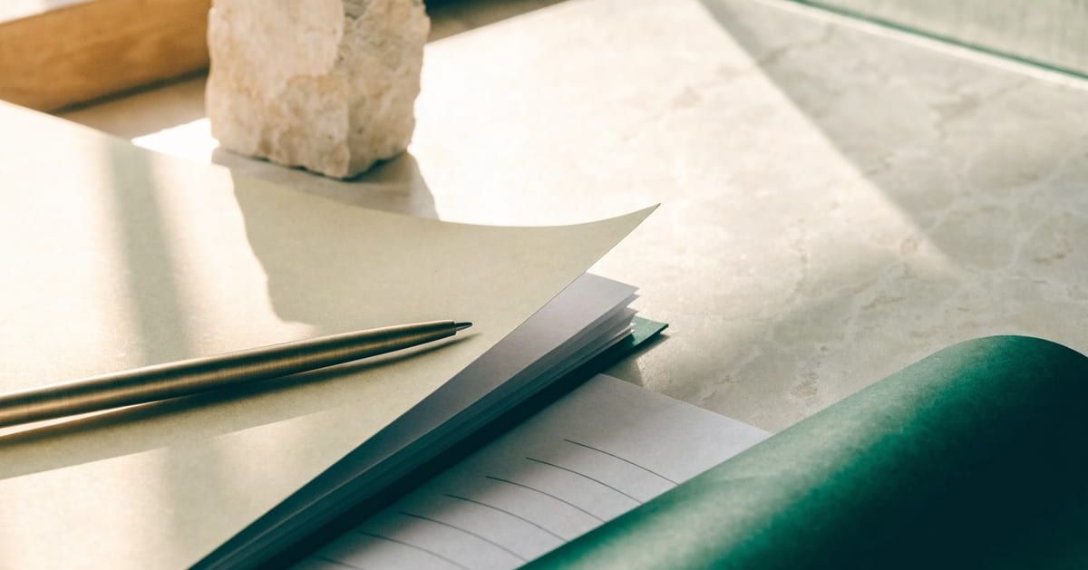 Document folder and brass pen on a sunlit stone desk