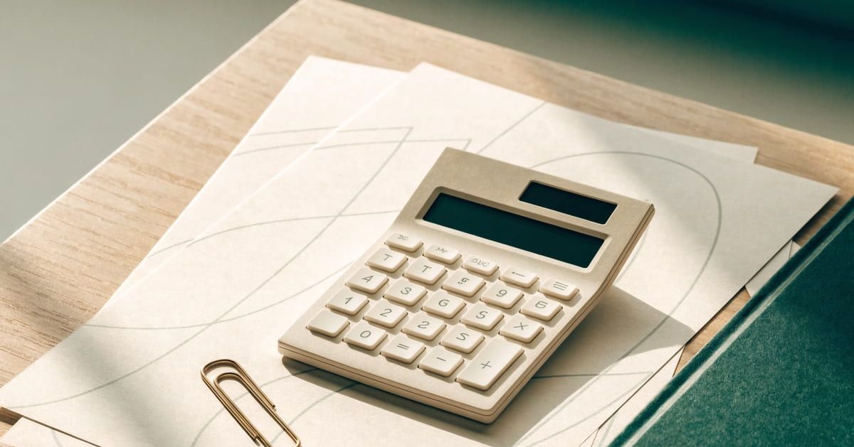 Calculator and financial papers beside a green notebook