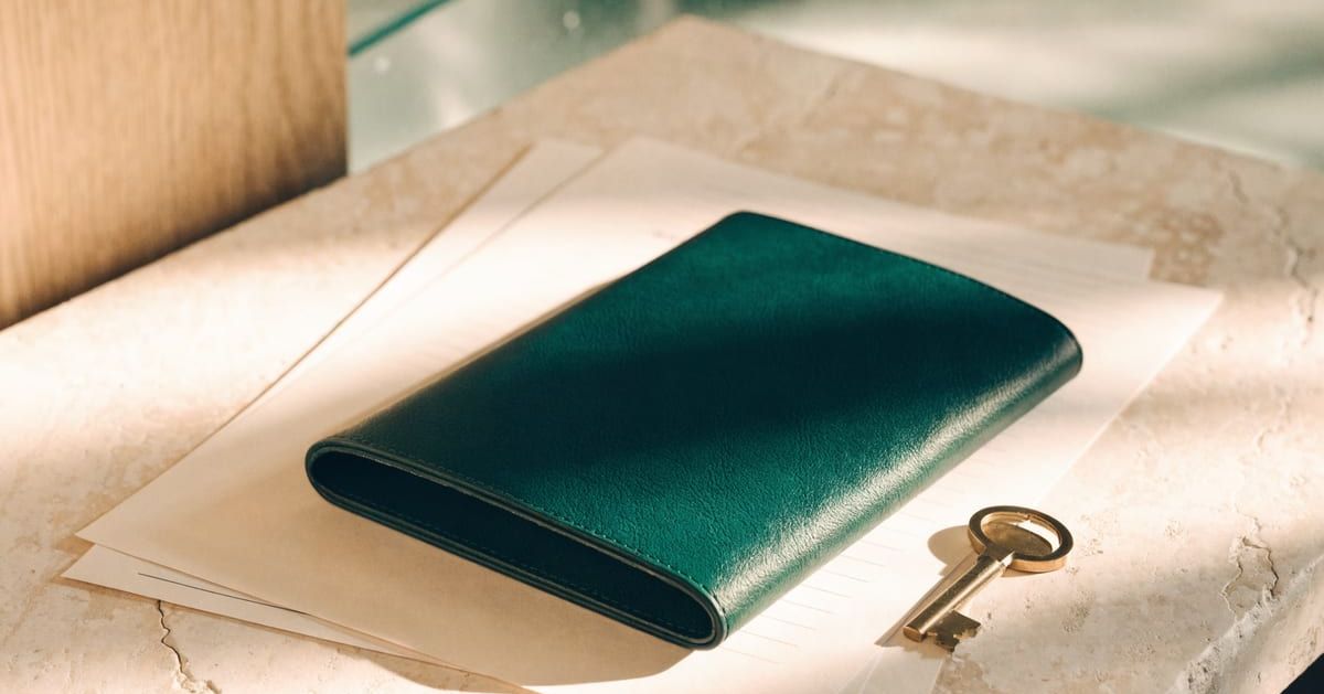 Green document holder and brass key on a limestone desk